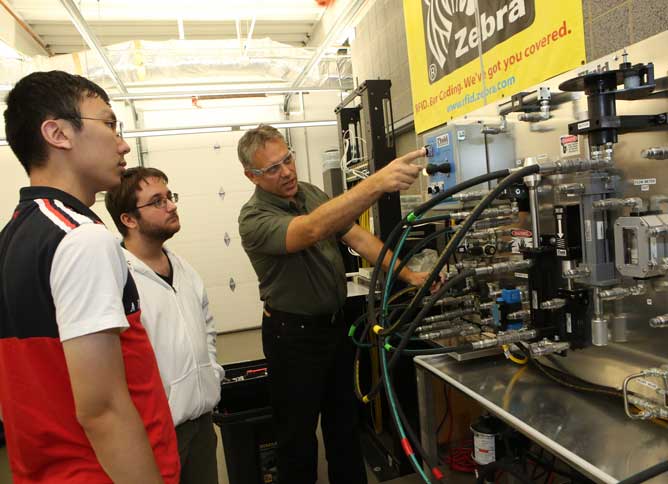 Oakton professor showing students how machinery works.