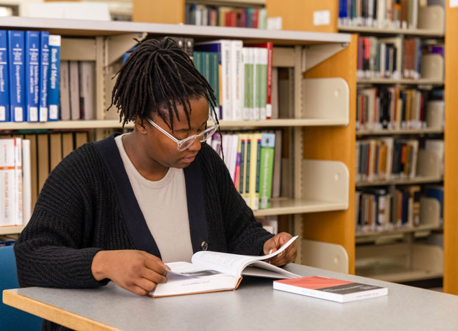 Student studying between library stacks.