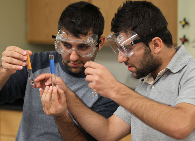 Two students with goggles and beakers.