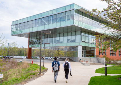 Two students walking towards an academic building.